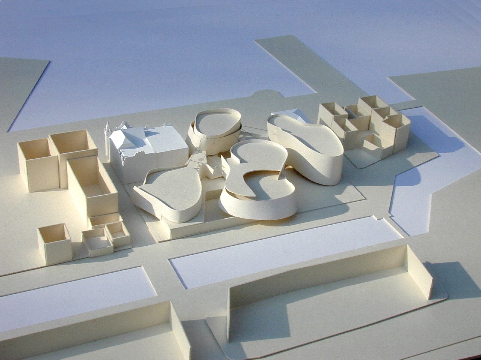 Project by Behnisch Architekturbuero, Ozeanum. Architectural model showing the curved building volumes among rectangular blocks on a site layout.
