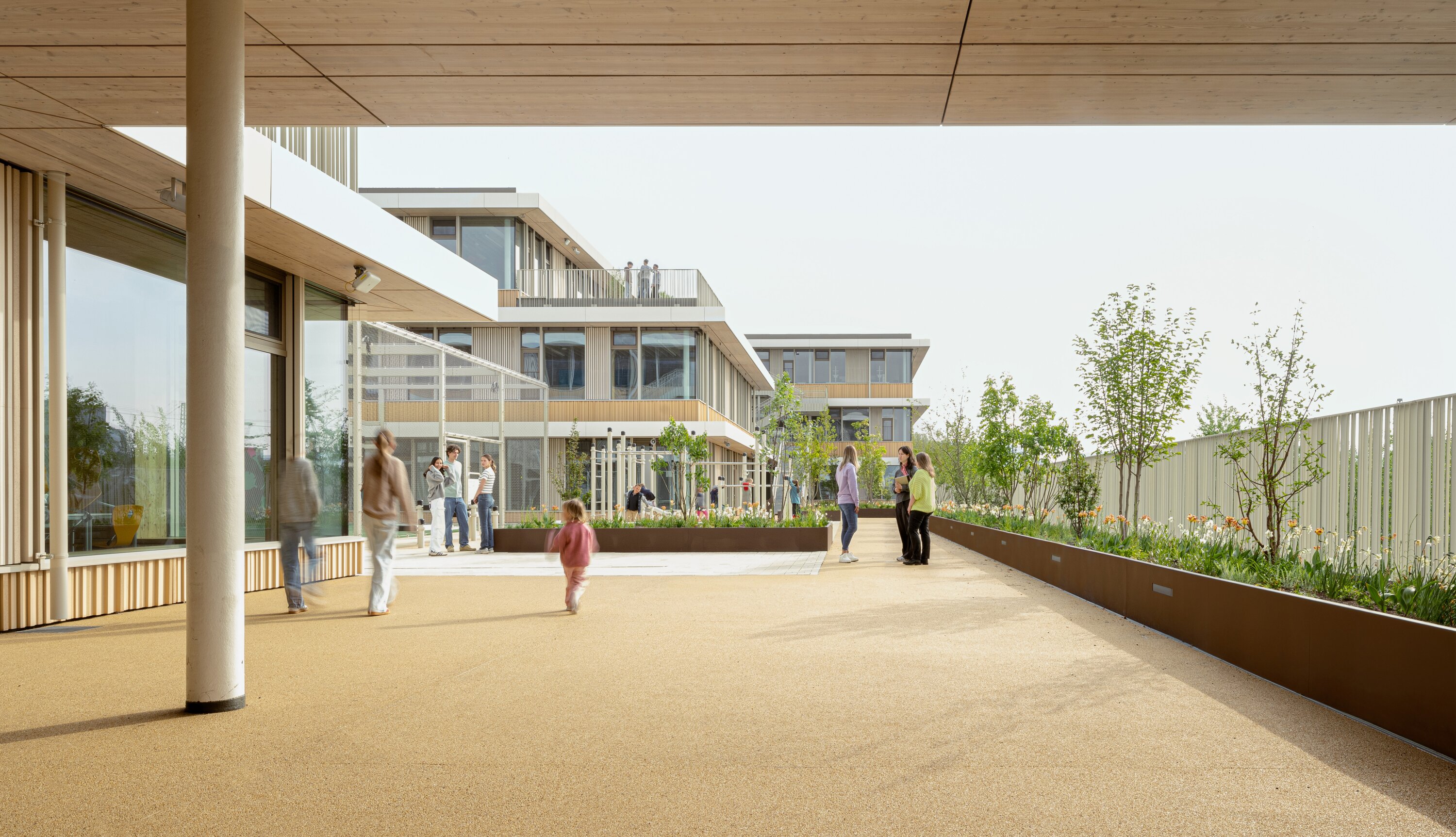 Project by Behnisch Architekturbuero, Digiteo Labs - 3 Research Buildings. Rectangular building with lit windows at dusk, set in an open grassy field under a dark blue sky.