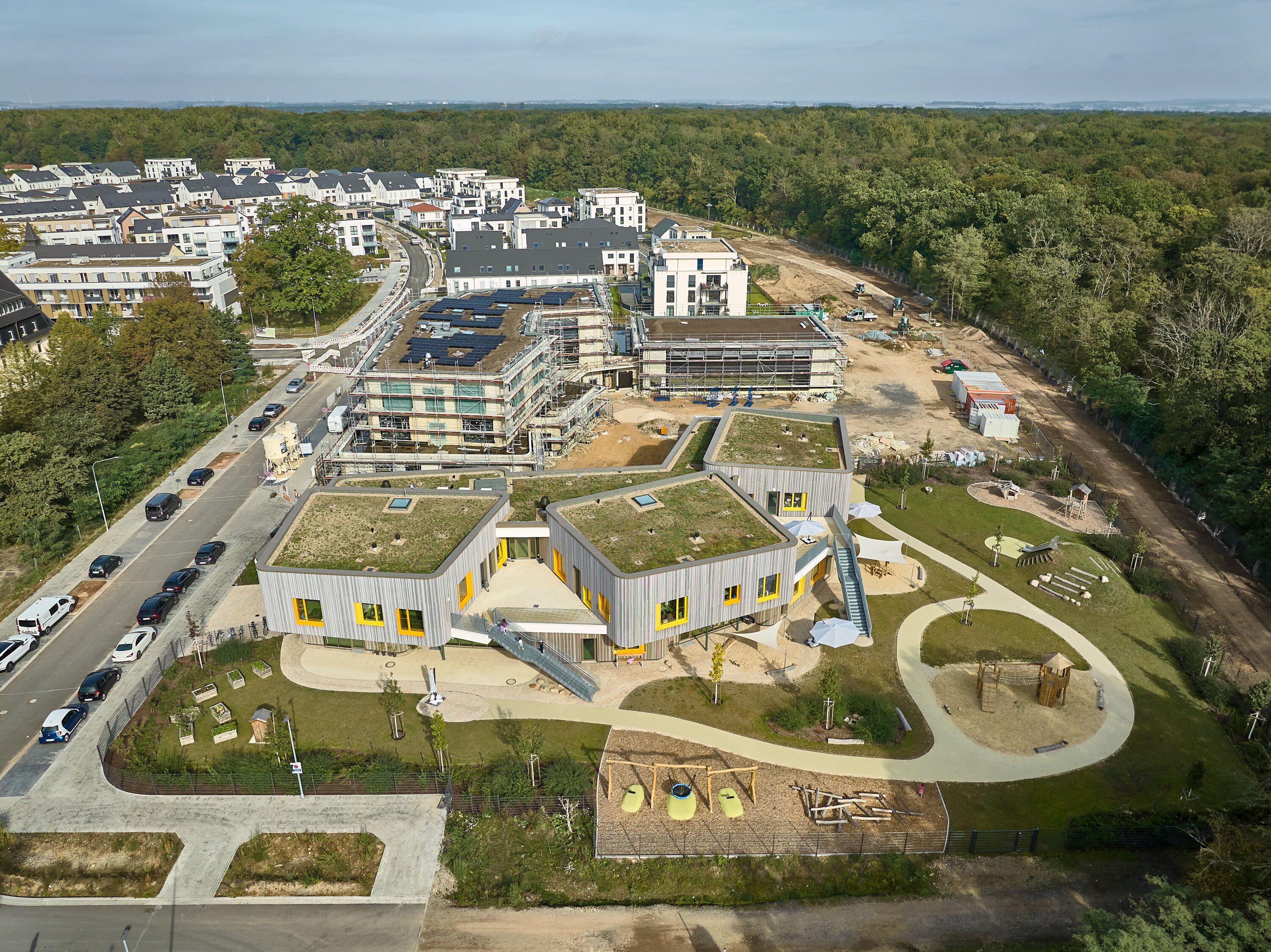 Project by Behnisch Architekturbuero, KiTa Pioneer-Kaserne. Aerial view of the building and the associated playground and garden area.