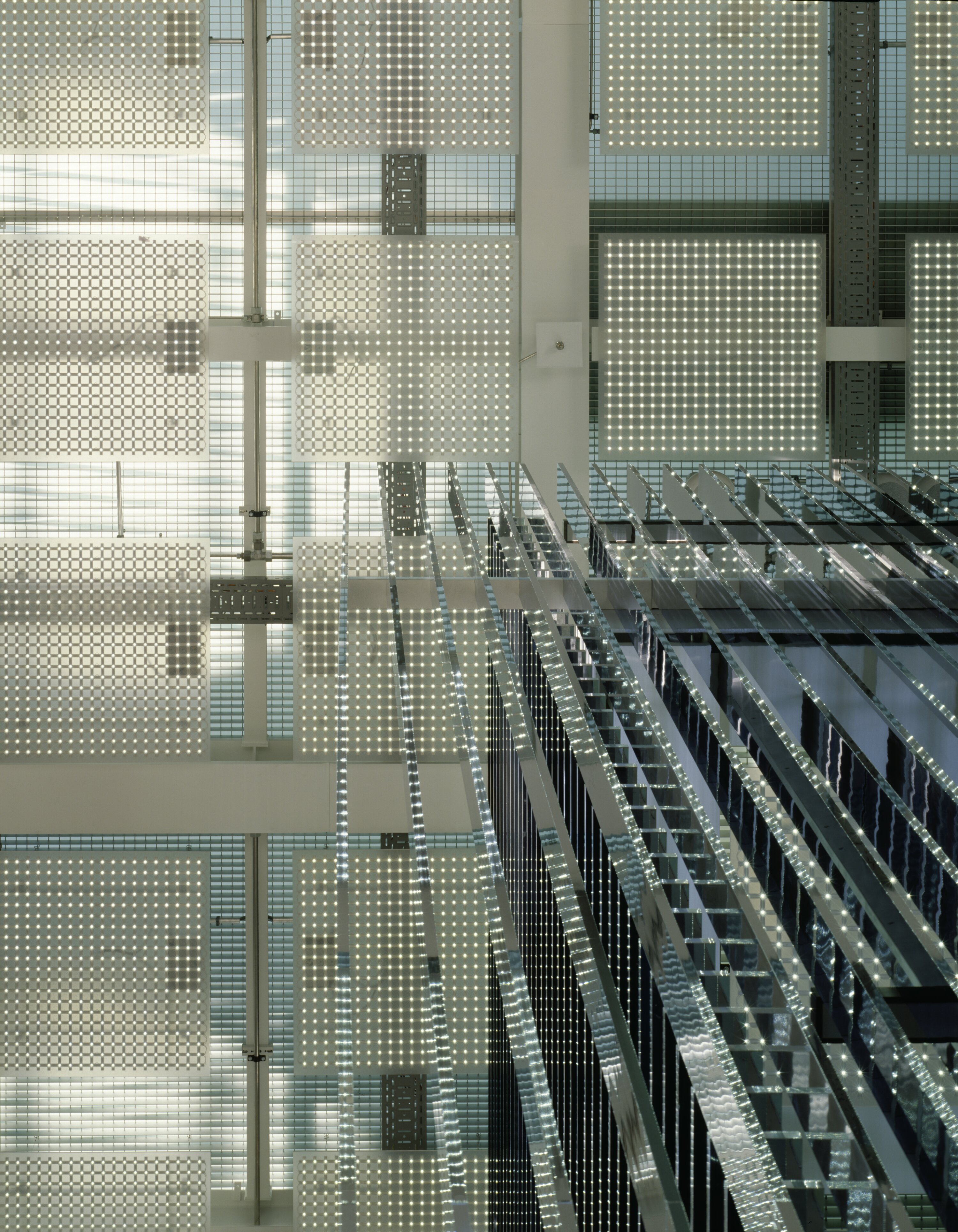 Project by Behnisch Architekturbuero, Haus im Haus. Ceiling view with grid of square light panels and reflective glass partitions in a modern interior.