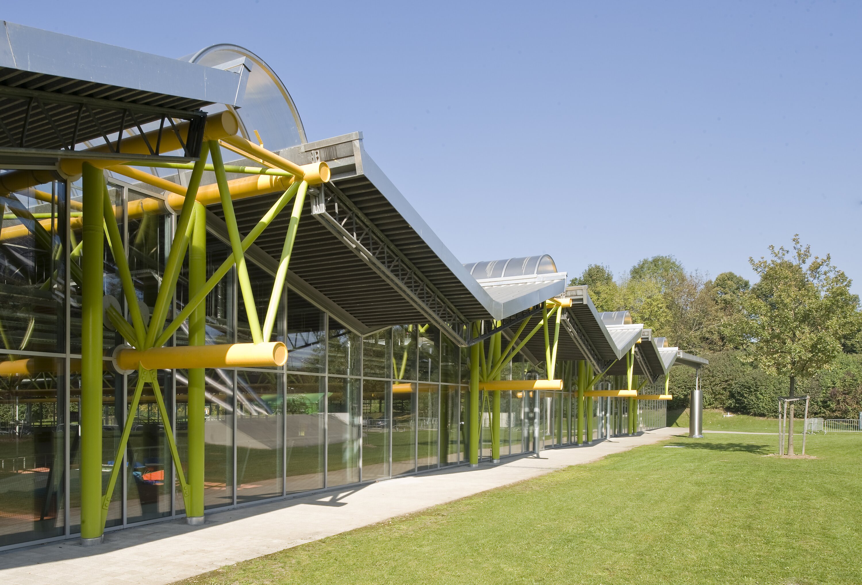 Project by Behnisch Architekturbuero, Werner-von-Linde-Halle. Modern glass building with curved roof sections and green steel supports.