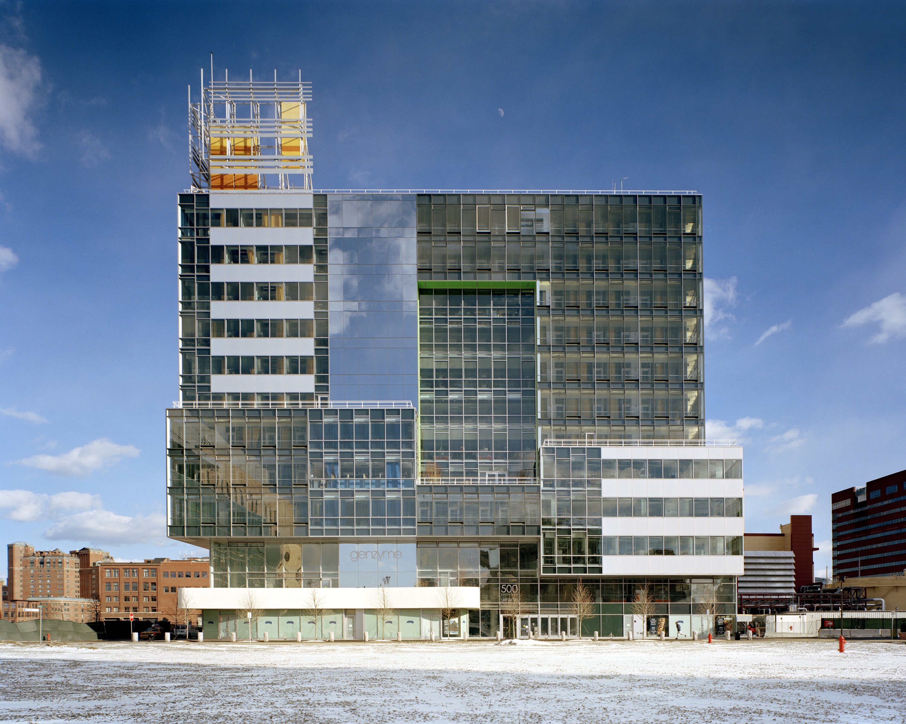 Project by Behnisch Architekturbuero, Genzyme Center. Front view of the modern office building at night with glass facade.