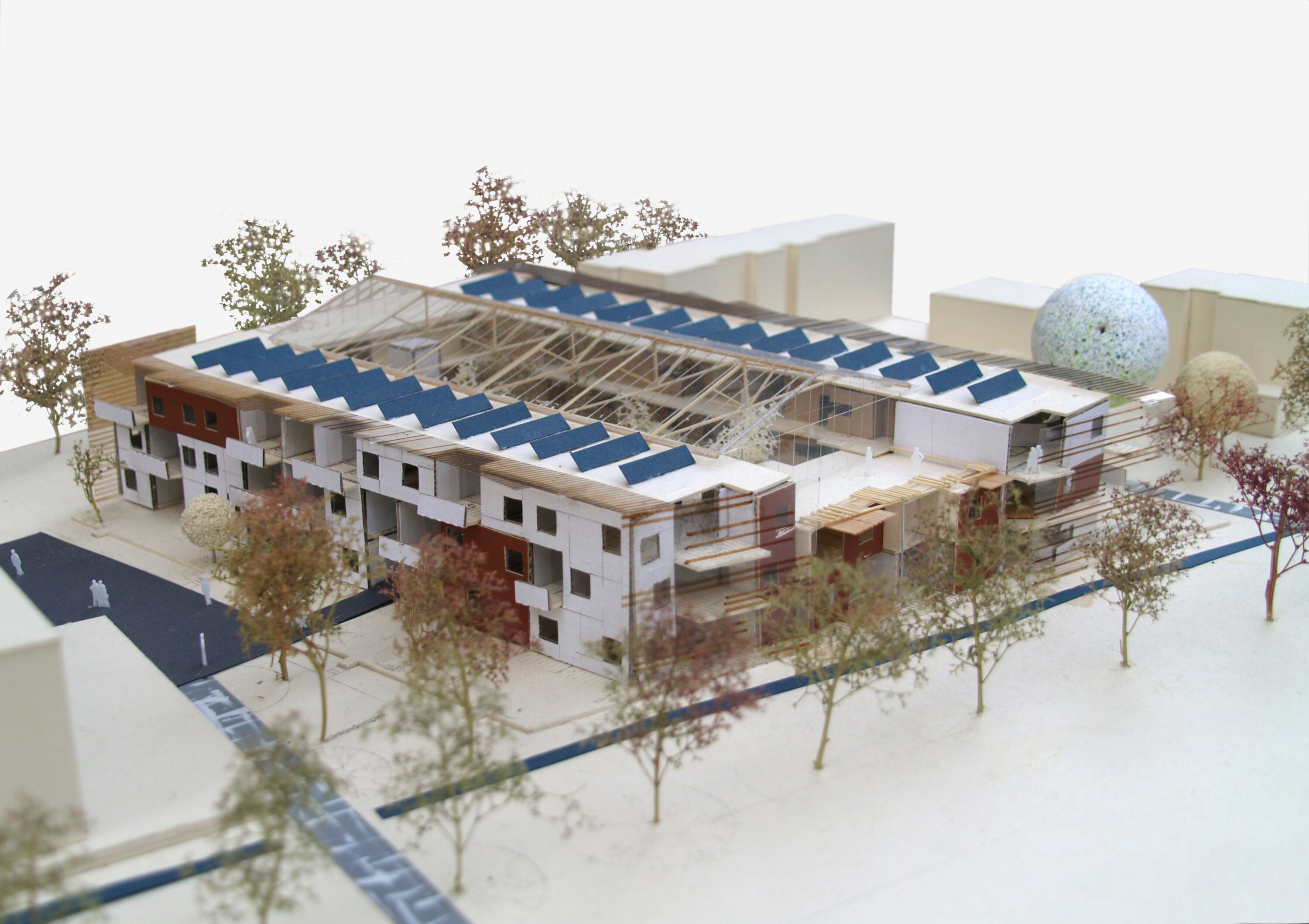 Project by Behnisch Architekturbuero, Residential Building Ingolstadt-Hollerstauden. Architectural model of the courtyard residential complex with solar panels, central atrium, trees and the surrounding area.